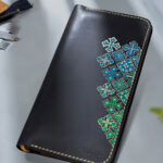 Handcrafted leather wallet with green and blue design.